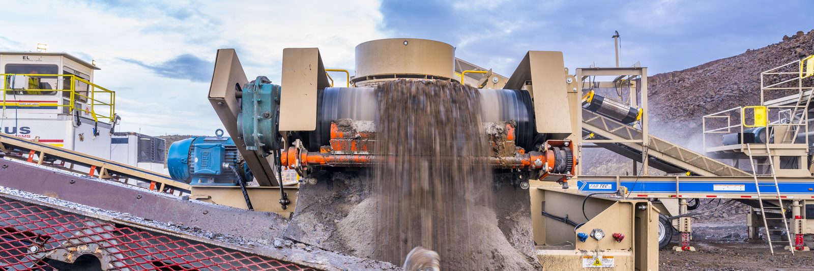 Crushed rock falling through a screen plant onto a conveyor